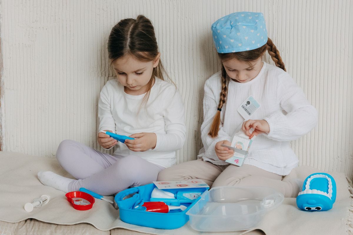 Two young girls playing with doctor toys indoors, exploring healthcare concepts through imaginative play.