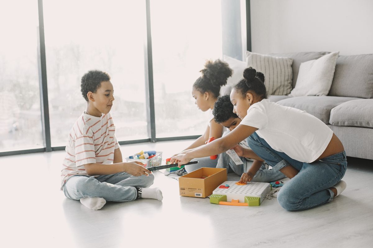 A group of children engaging in play with toys and games on a sunny day indoors.