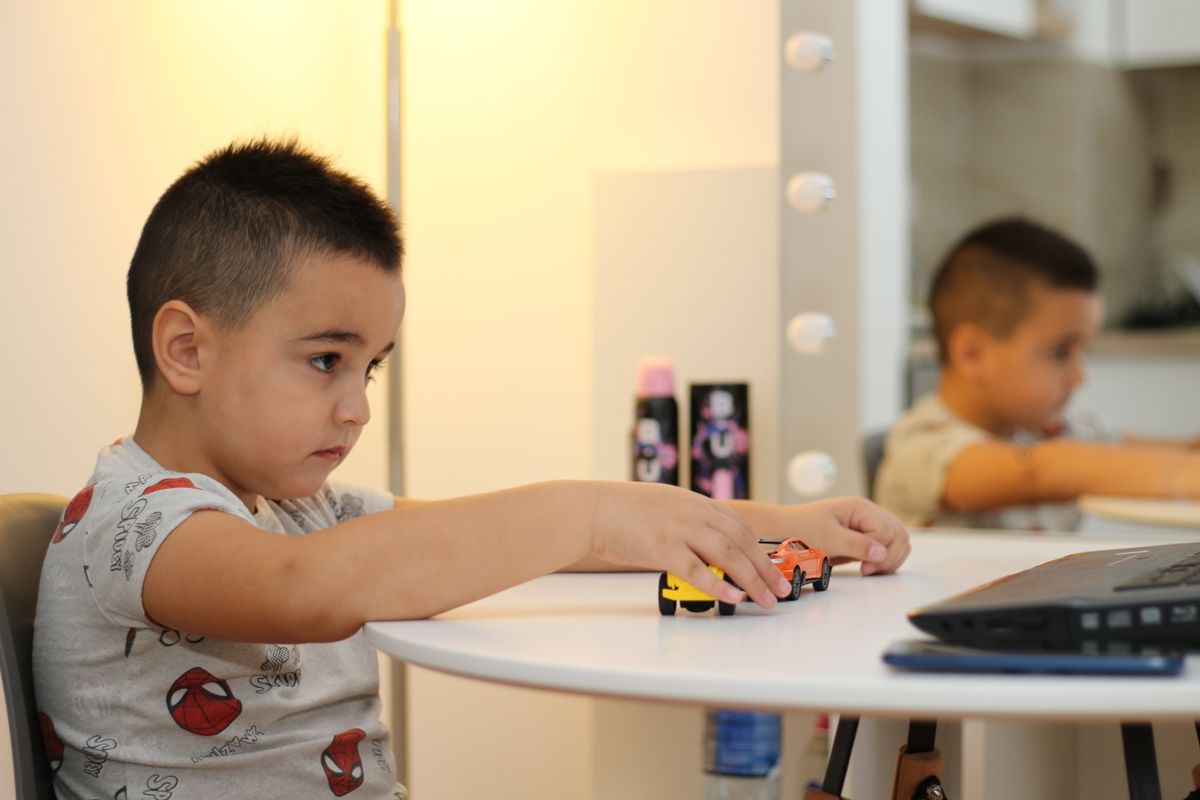 A young boy engaged in play with toy cars on a table in a cozy home setting.