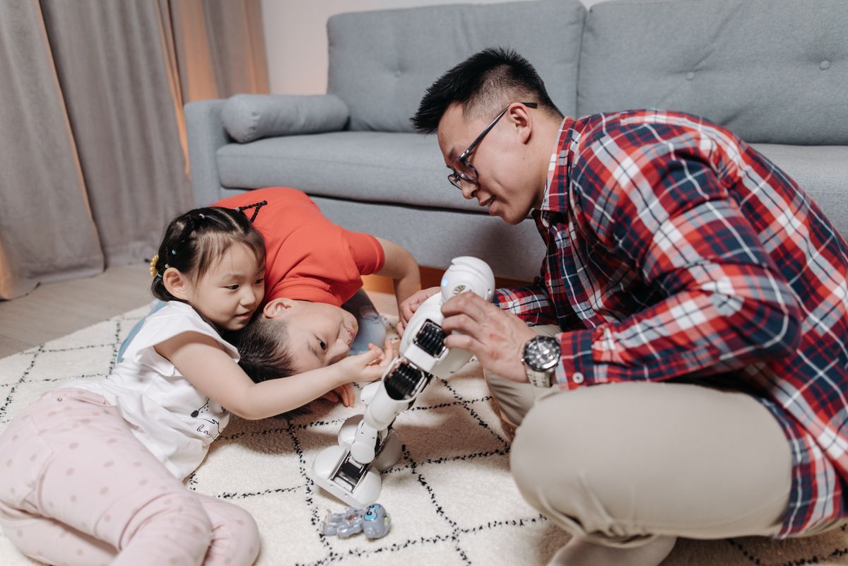 Family bonding time with a father and kids playing creatively with a robot toy.