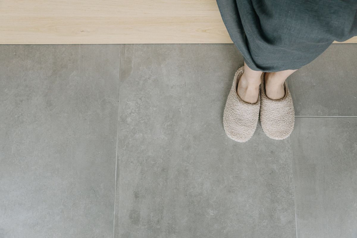 Overhead view of feet in plush slippers on a modern tiled floor, creating a cozy indoor vibe.