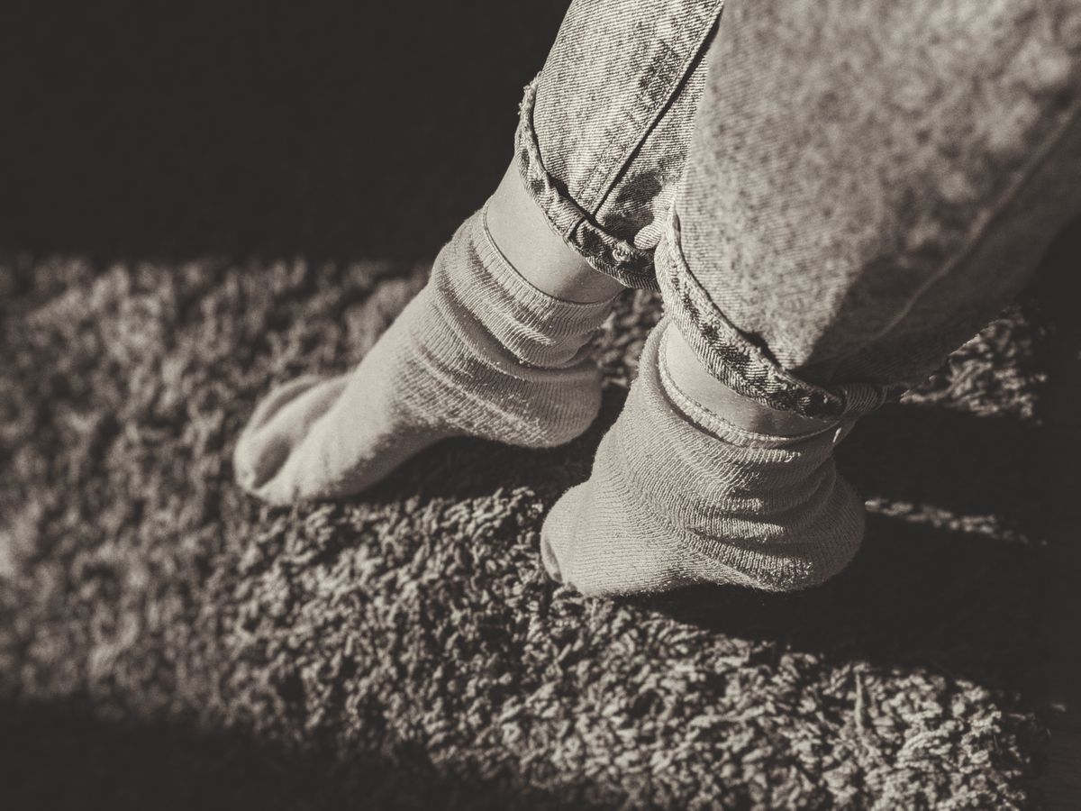 Relaxing feet in socks and jeans on a carpet, enjoying cozy indoor atmosphere.
