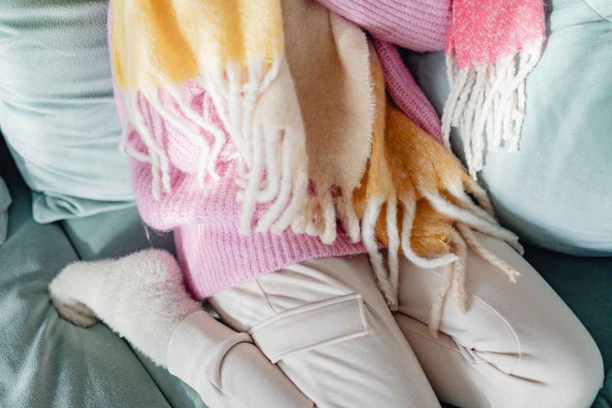 A relaxing moment with cozy clothing, featuring soft scarves, fuzzy socks, and a pastel palette on a plush sofa.