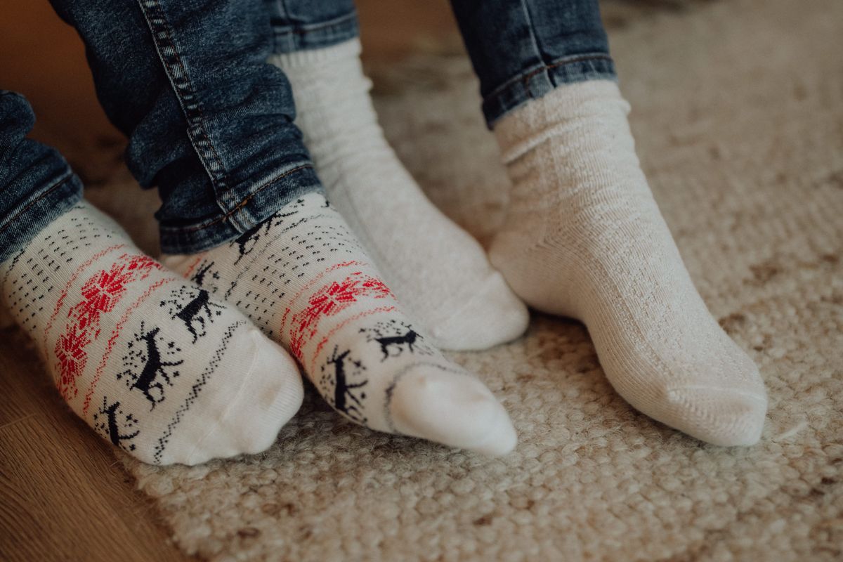 Two people wearing festive socks on a cozy carpet floor indoors.