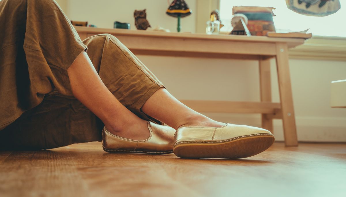 A close-up of legs wearing comfortable slip-on shoes indoors, exuding relaxation and style.