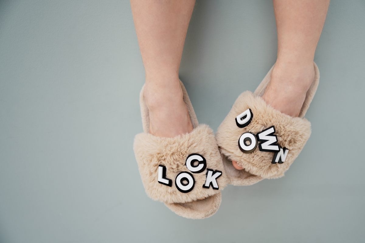 Close-up of beige furry slippers with 'lockdown' text, highlighting comfort and home lifestyle.