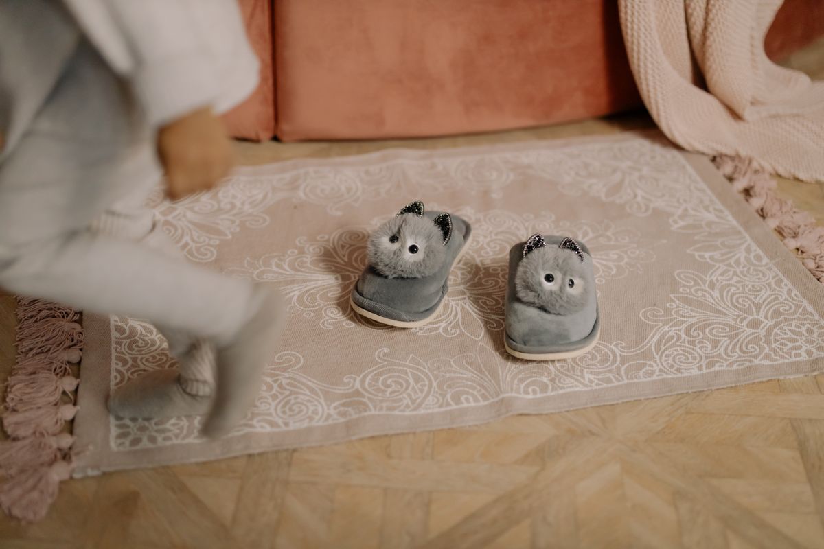 Adorable plush animal slippers on a decorative rug in a cozy child's room setting.