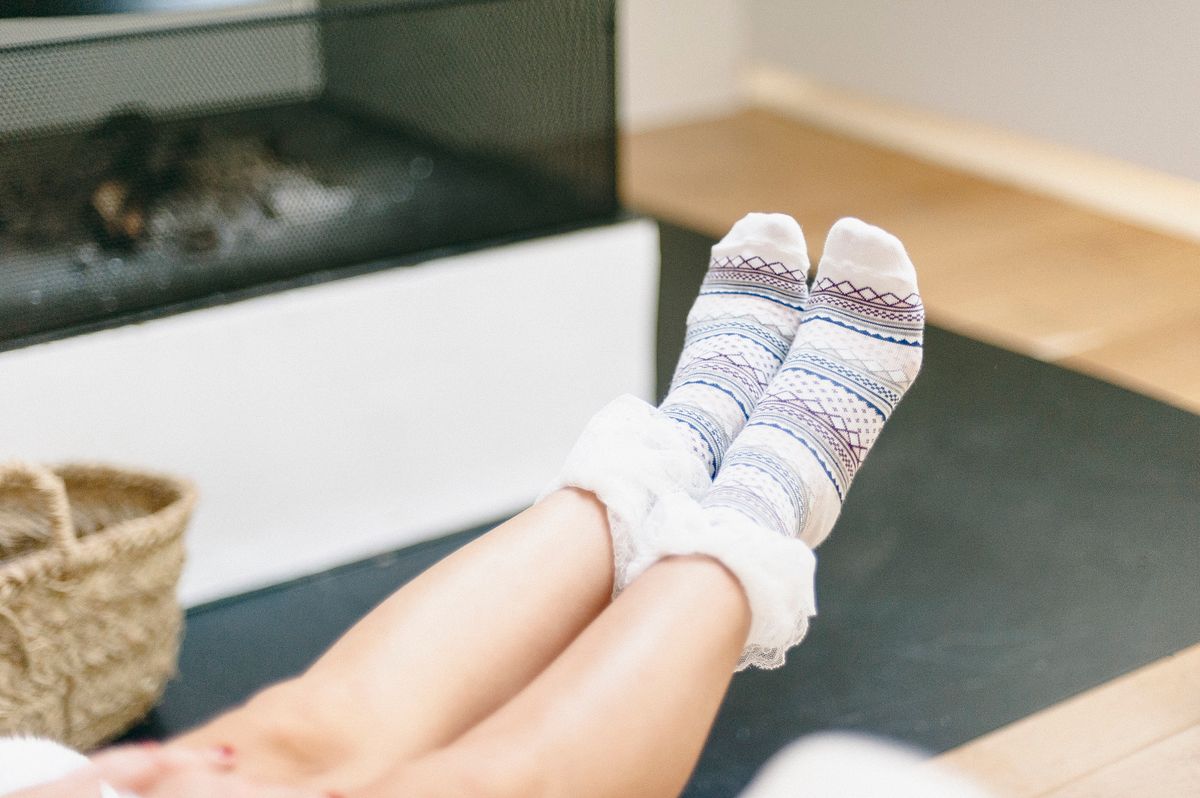 Relaxing indoors with warm patterned socks in front of a cozy fireplace. Ideal for winter lifestyle imagery.