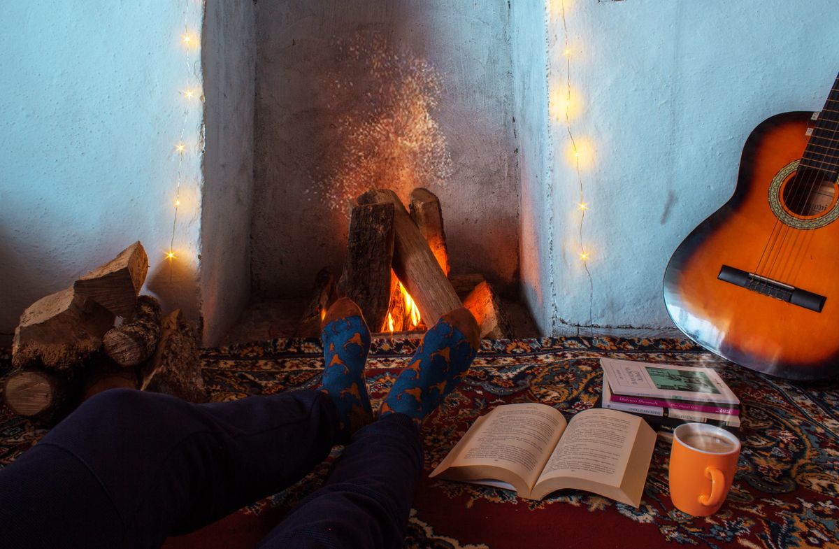 Warm indoor setting with a fireplace, guitar, and book creating a cozy atmosphere.
