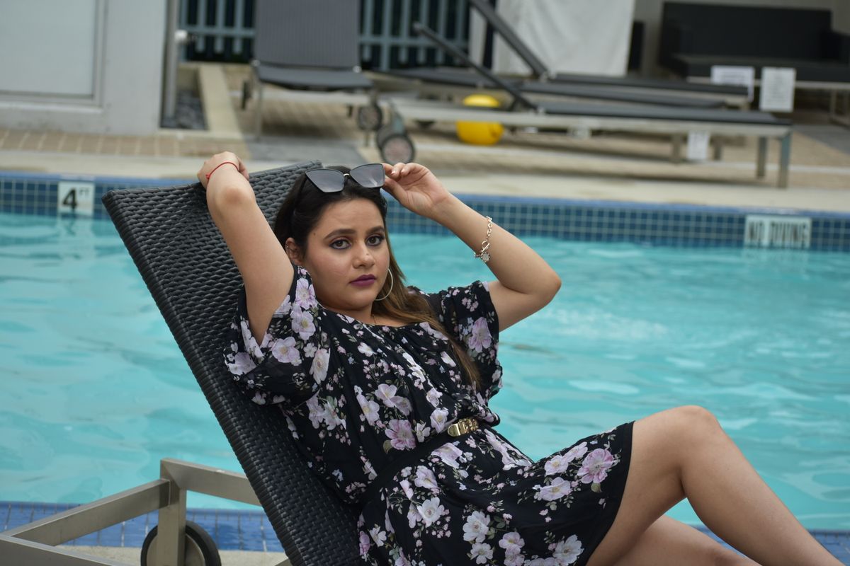 Stylish woman in floral dress relaxing by the pool in Vancouver summer.