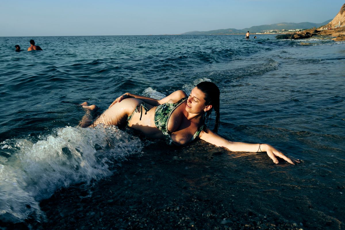 A woman in a bikini enjoys relaxing on a sunny beach with gentle waves.