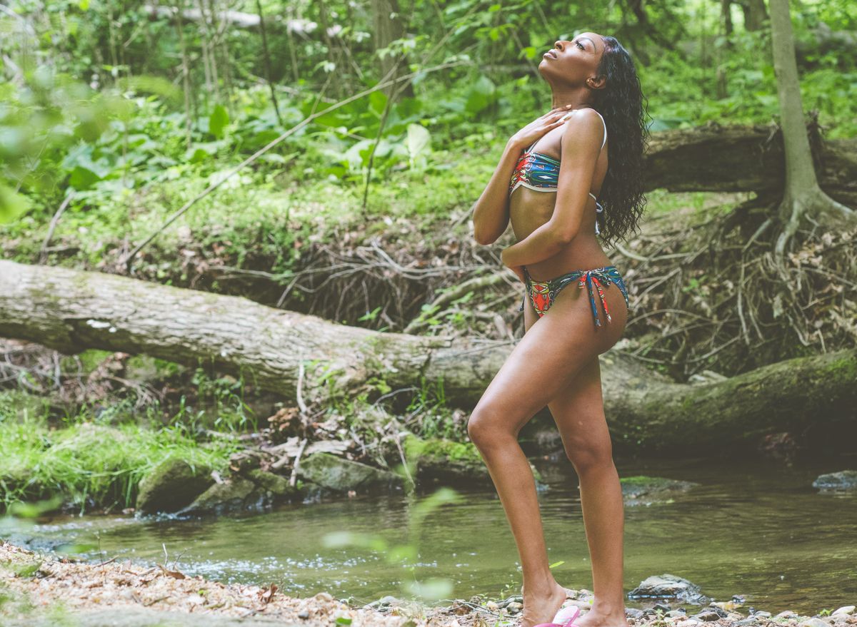Young woman enjoying a tranquil moment by a forest stream, embodying summer relaxation and natural beauty.