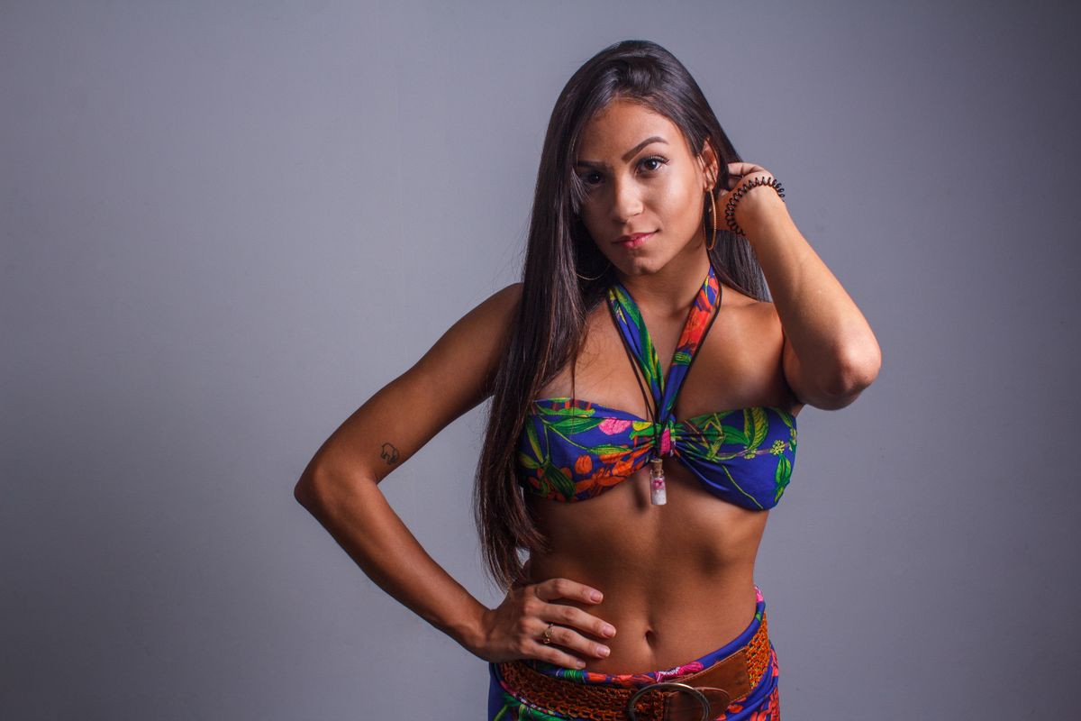 Portrait of a fashionable adult woman posing confidently indoors in a vibrant floral bikini top.