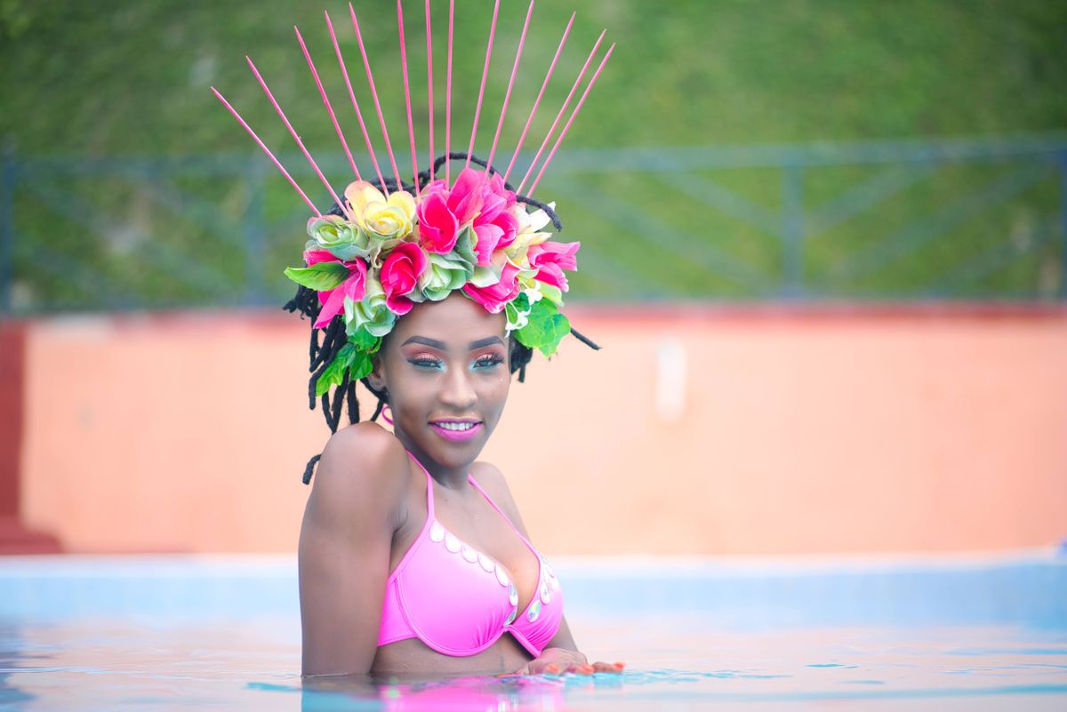 A beautiful woman in a floral headdress smiles while swimming in a pool.