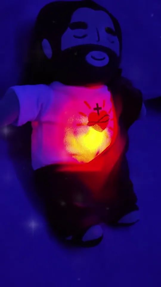 Close-up of the plush in a dark room, the Sacred Heart lighting up
