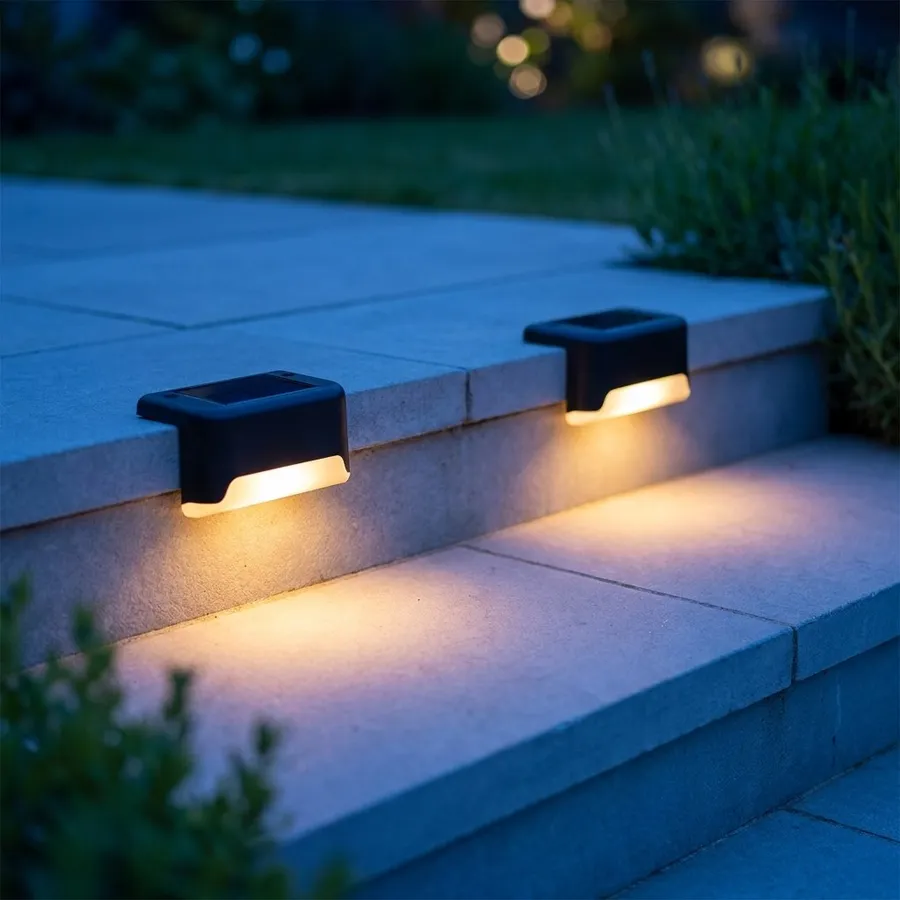 Two solar step lights washing warm light down a pale grey stone garden step at dusk