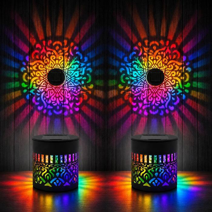 Two mandala lights projecting symmetric rainbow bursts on dark wood