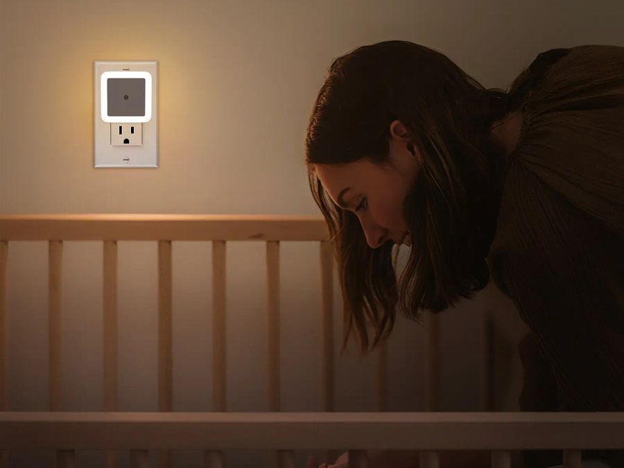 Parent checking on baby with night light glowing
