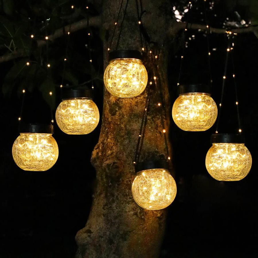 Warm-white crackle-glass solar hanging lanterns glowing gold in a tree at night
