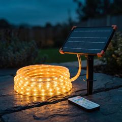 Solar LED rope light coiled beside its solar panel stake and remote at dusk