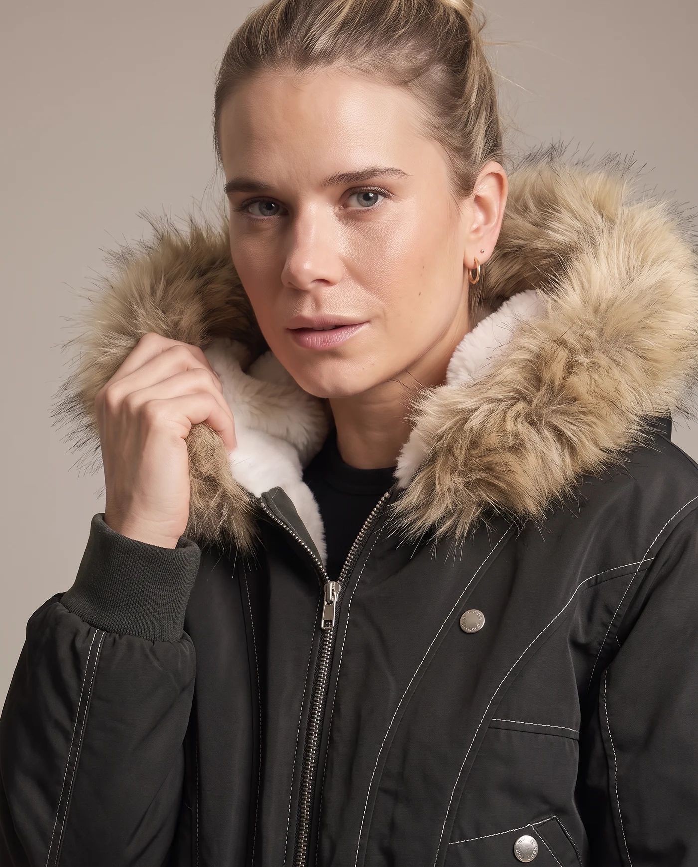 Close shot of the black bomber jacket with the tan faux fur hood trim framing the face