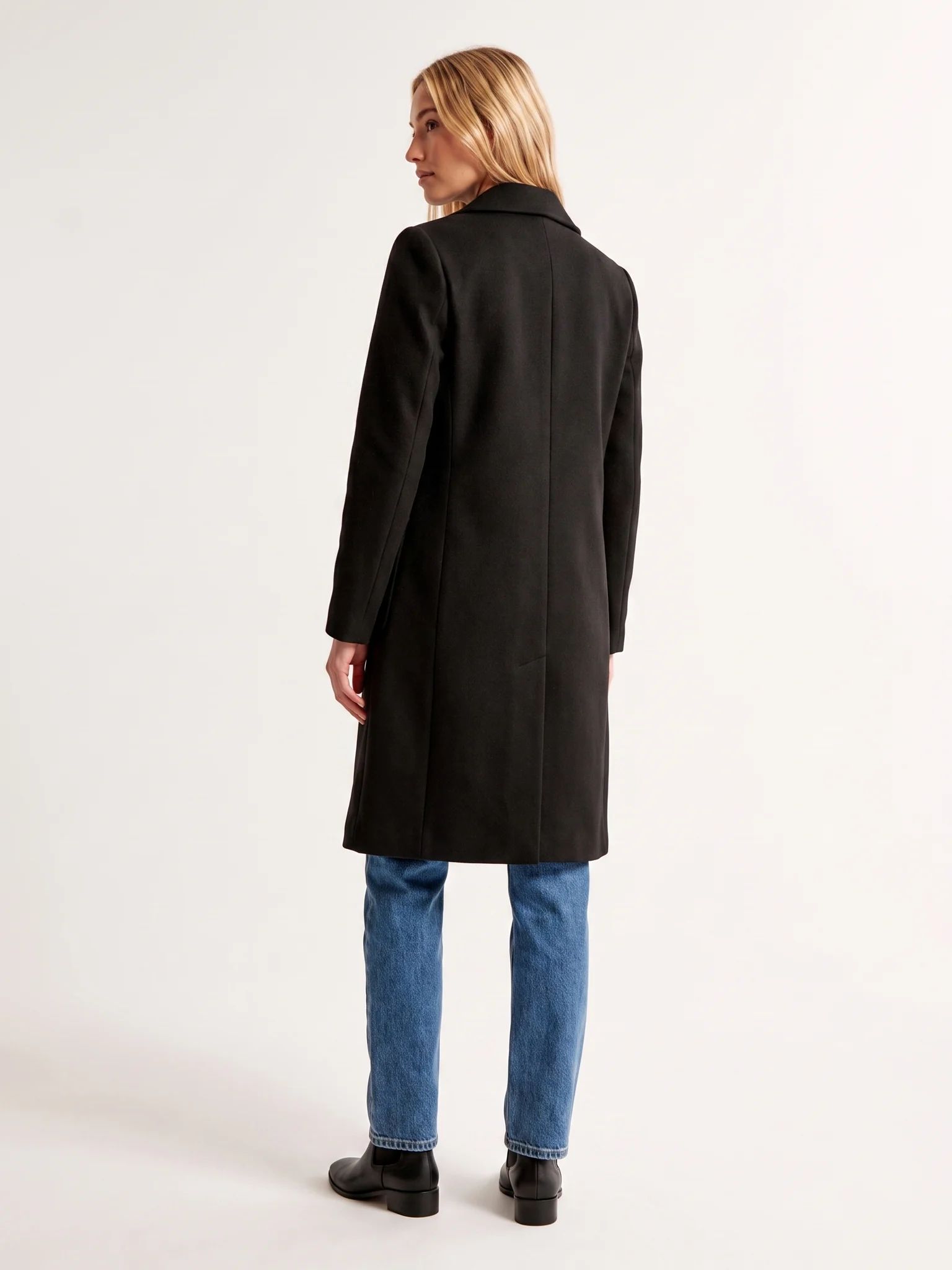 The back of the Black wool-blend coat on a model, showing the shoulder line and the below-the-knee hem