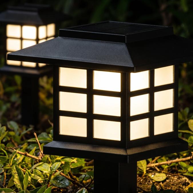 Close-up of a solar lantern path light glowing warm white at night