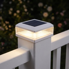 White solar post cap light on a white vinyl fence post at night