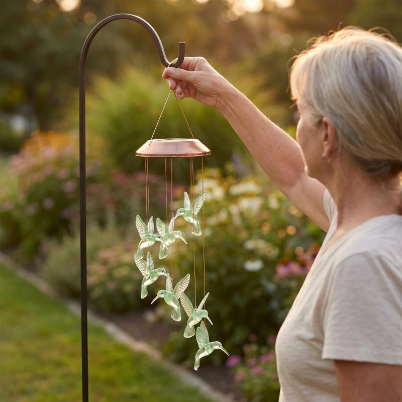 A woman hanging the chime on a garden shepherd hook